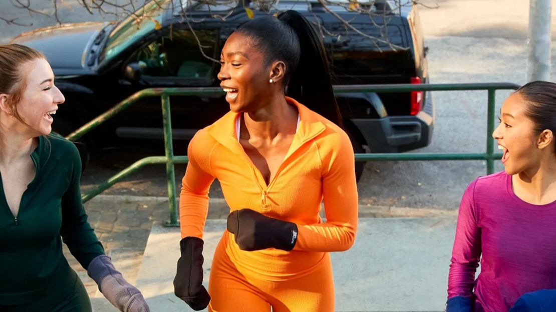 Three women wearing workout clothes and runmitts