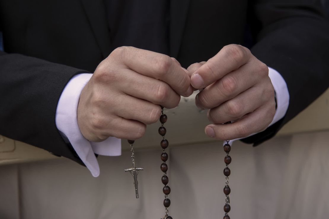 Una persona sostiene un rosario mientras se espera el anuncio de un nuevo papa.
