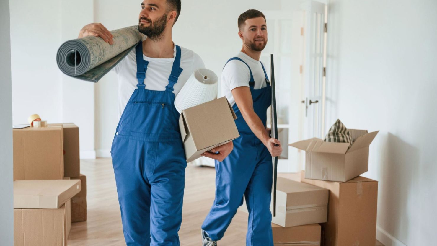 Moving crew carrying household items out of a house.