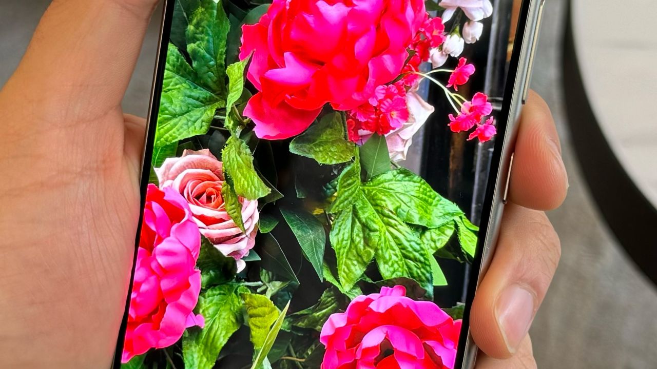 A hand holds the Galaxy S24 Ultra displaying a slightly more saturated photo of a fake rose