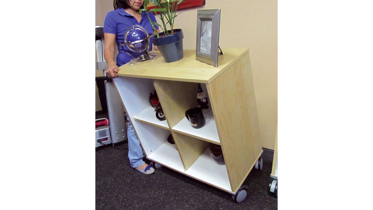 Woman tilting cabinet, all items on top staying in place.