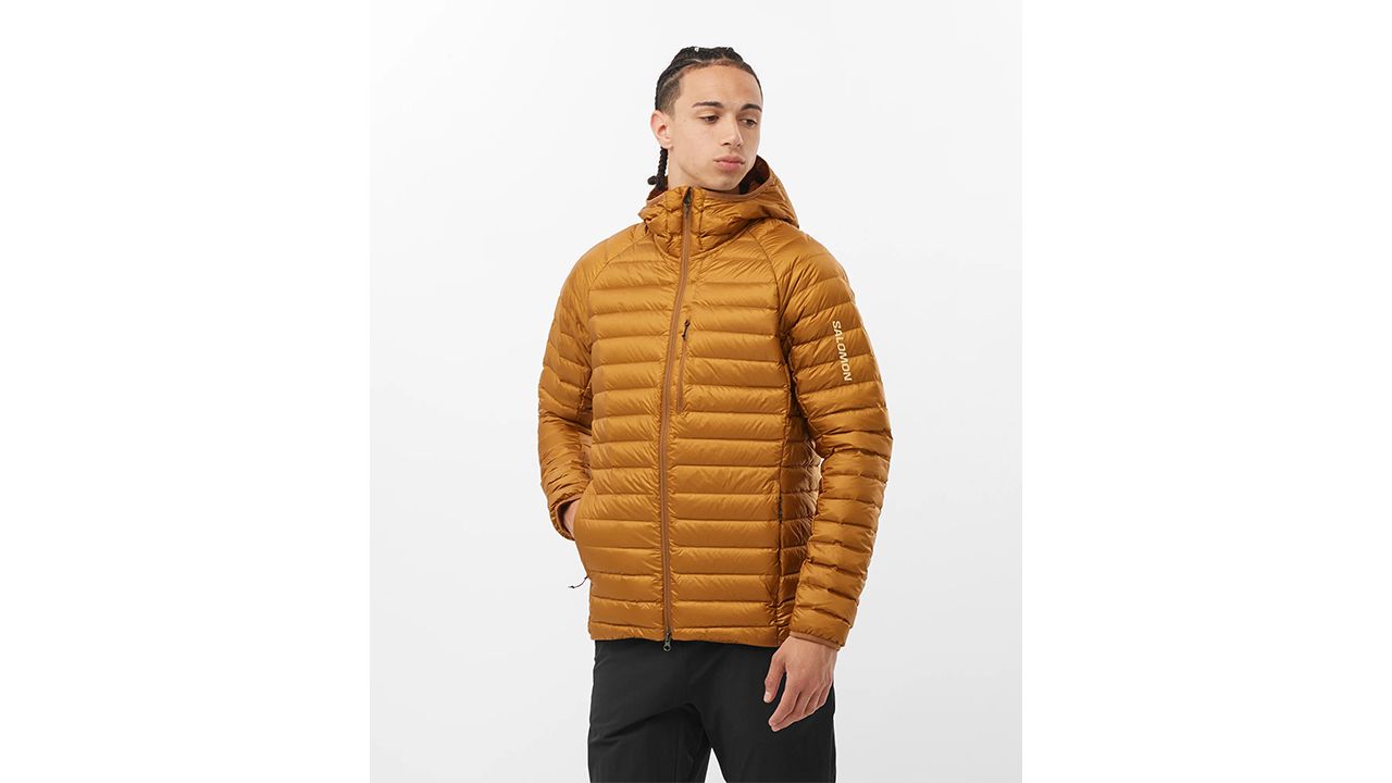 A photo of a person wearing a copper-colored Salomon Elixir Micro Down Hooded jacket