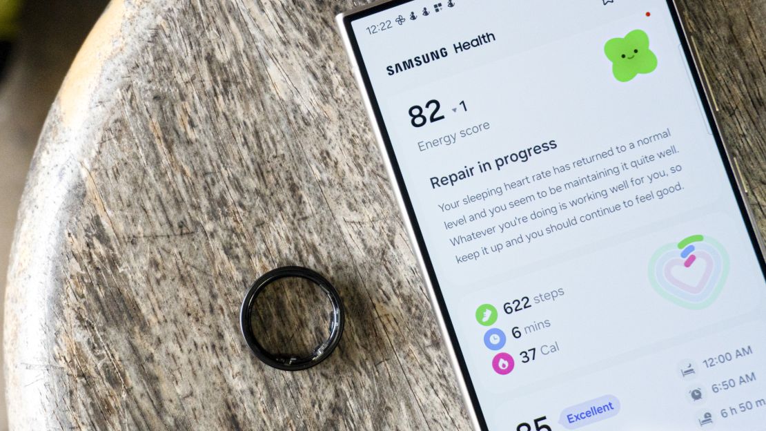 Black Samsung Galaxy Ring next to phone showing Energy score on app.