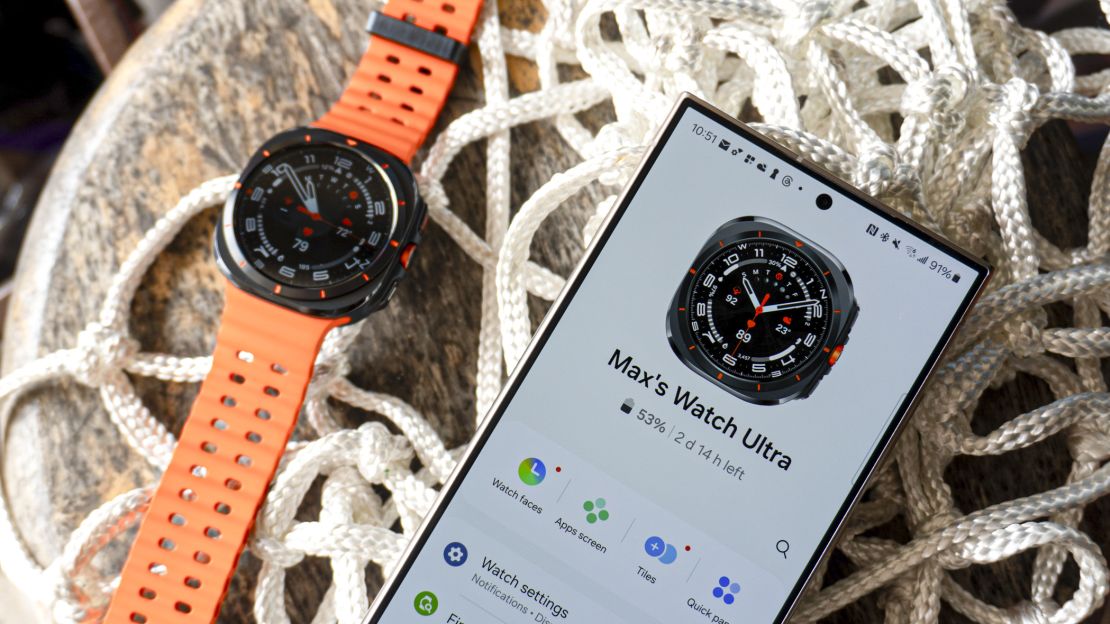 Orange Samsung Galaxy Watch Ultra next to phone with watch app opened.