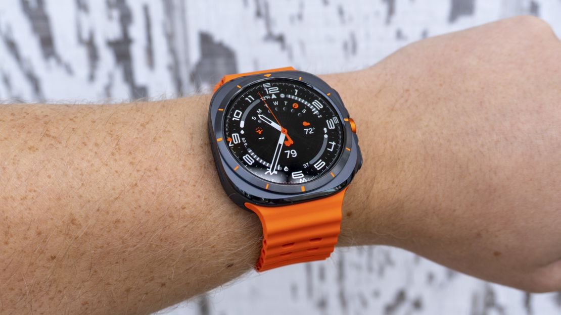 Orange Samsung Galaxy Watch Ultra on wrist with white background.