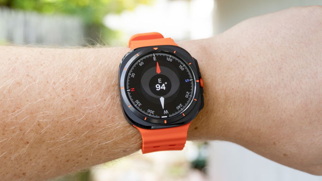 Orange Samsung Galaxy Watch with screen showing compass directions.