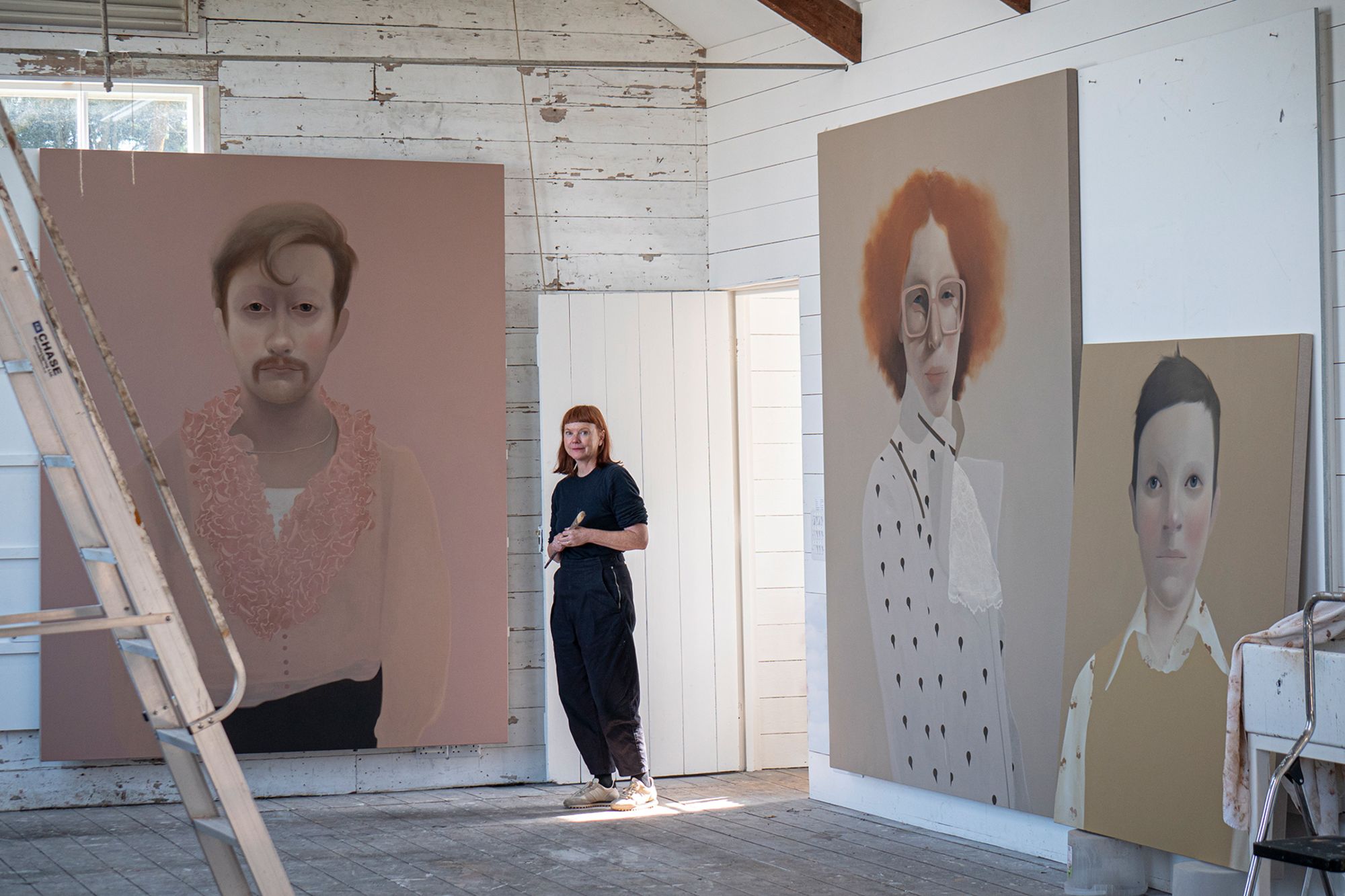 Painter Sarah Ball, in her studio with her large-scale works (left to right) "Pink Elliot," "Elliot" and "Alys, Laurel and Hardy."