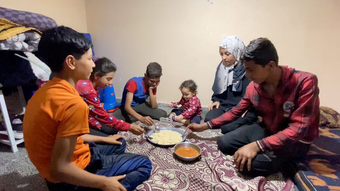 Um Hassan (second from right) is pictured eating food provided by World Central Kitchen on May 1, in Deir al-Balah, in central Gaza. The mother told CNN her toddler (center) is "happy to eat rice."