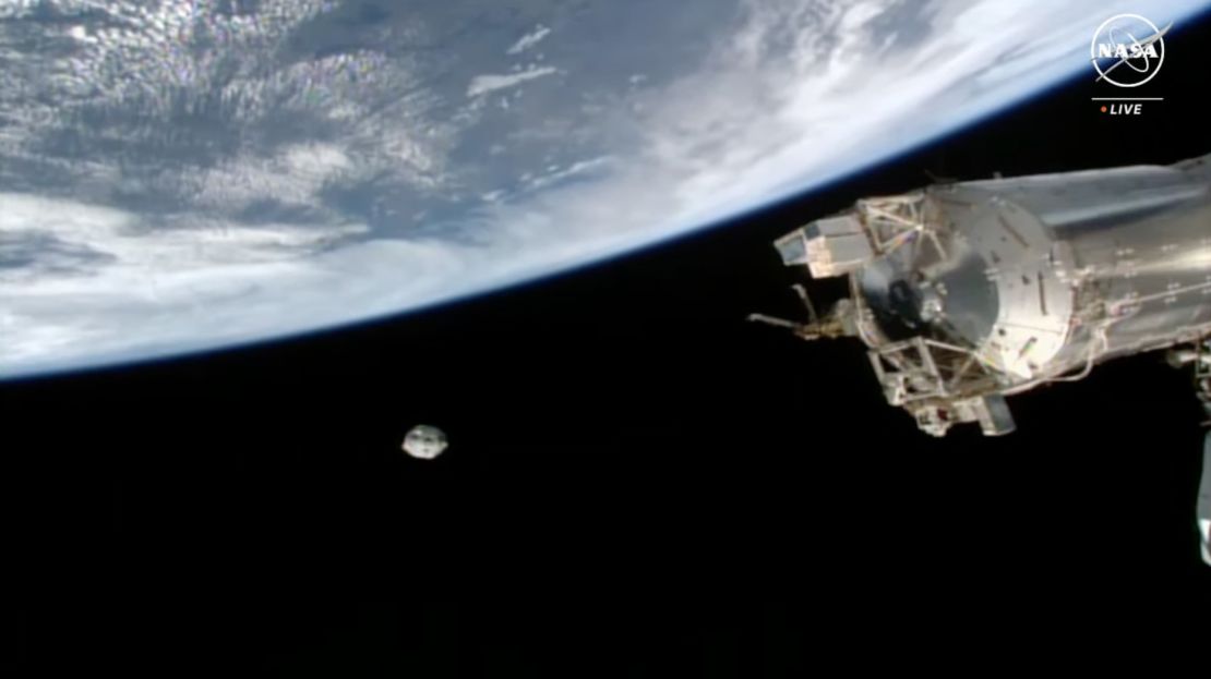 The Boeing Starliner spacecraft can be seen in the distance, with Earth in the background, as it travels to the International Space Station.