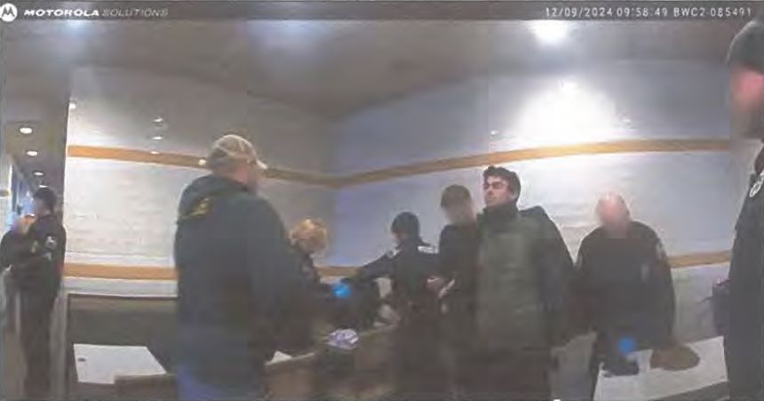 A still from bodycam footage of police searching Luigi Mangione’s backpack.