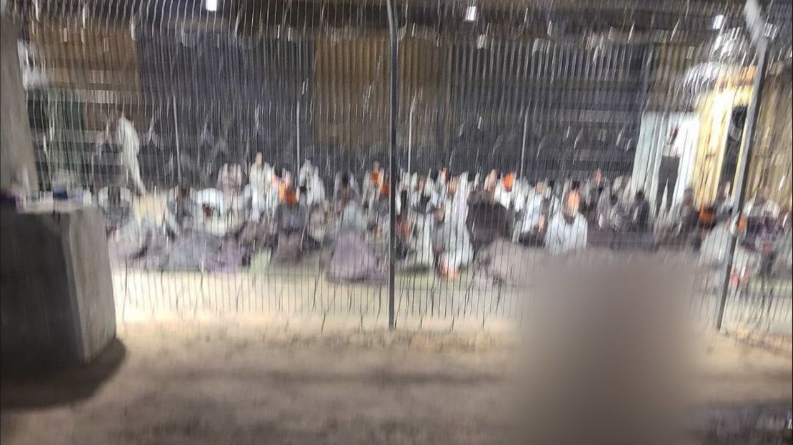 A leaked photograph of an enclosure where detainees in gray tracksuits are seen blindfolded and sitting on paper-thin mattresses. CNN was able to geolocate the hangar in the Sde Teiman facility. A portion of this image has been blurred by CNN to protect the identity of the source.