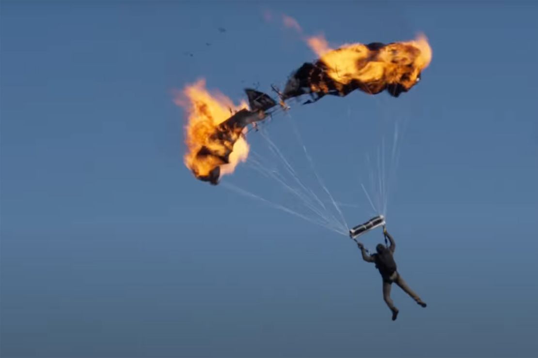 In this screenshot, actor Tom Cruise performs a stunt with a parachute that is on fire for the film
