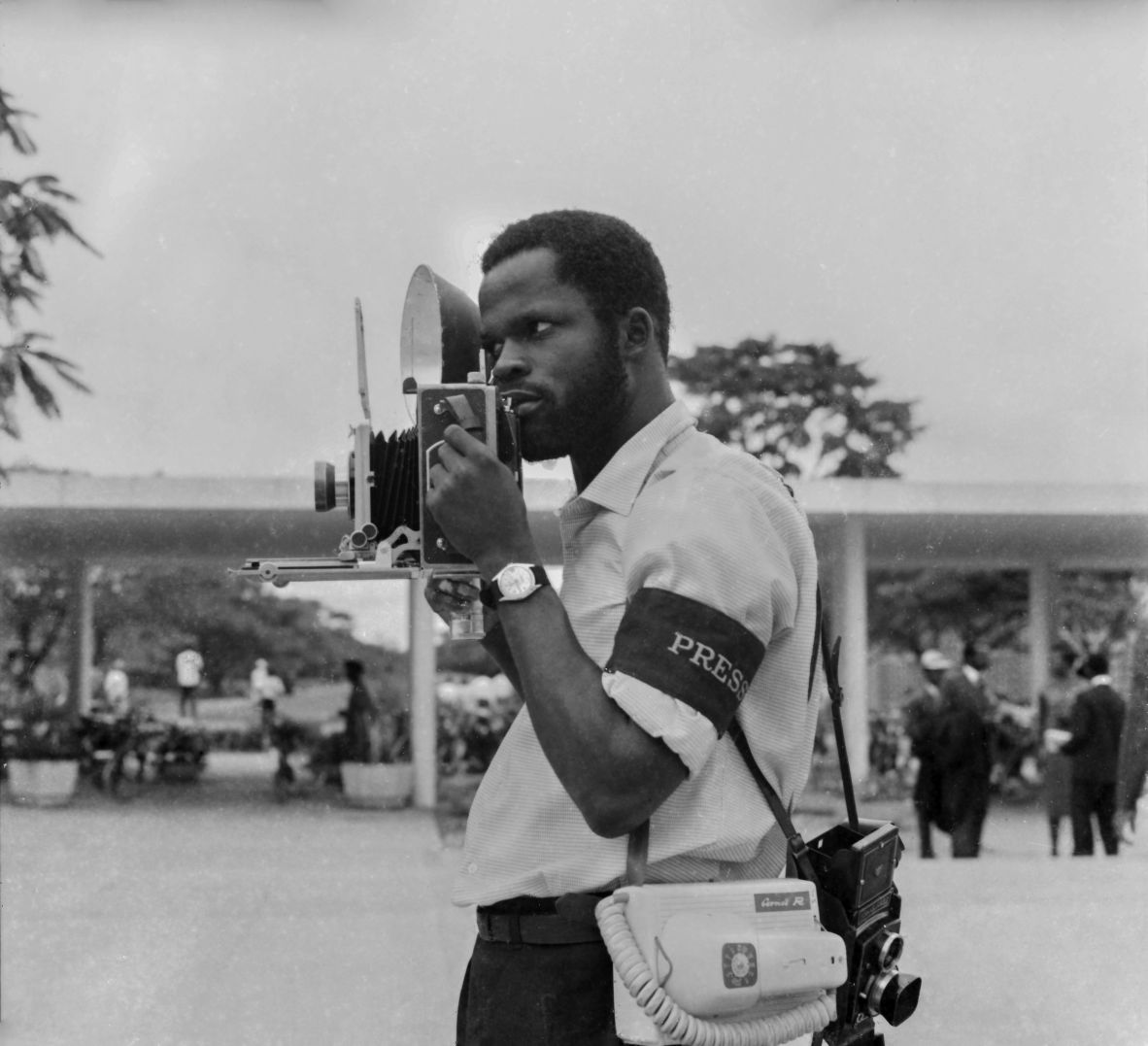 Ojeikere with his camera in 1956. The exhibition, titled “An Exacting Eye” features lesser-known photographs from his portfolio.