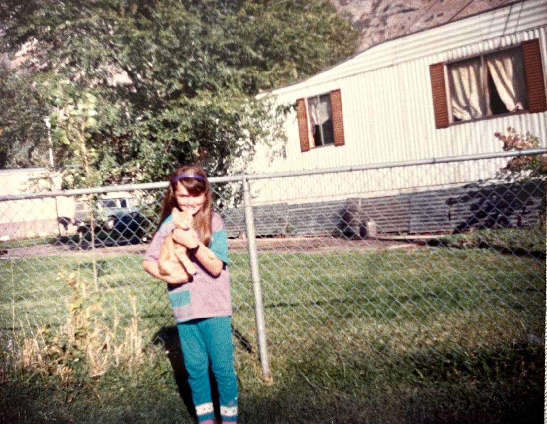 Carrie Sheffield with the family cat Buff, approximately age 11 in fifth grade in the family backyard of their Springville, Utah mobile home park.