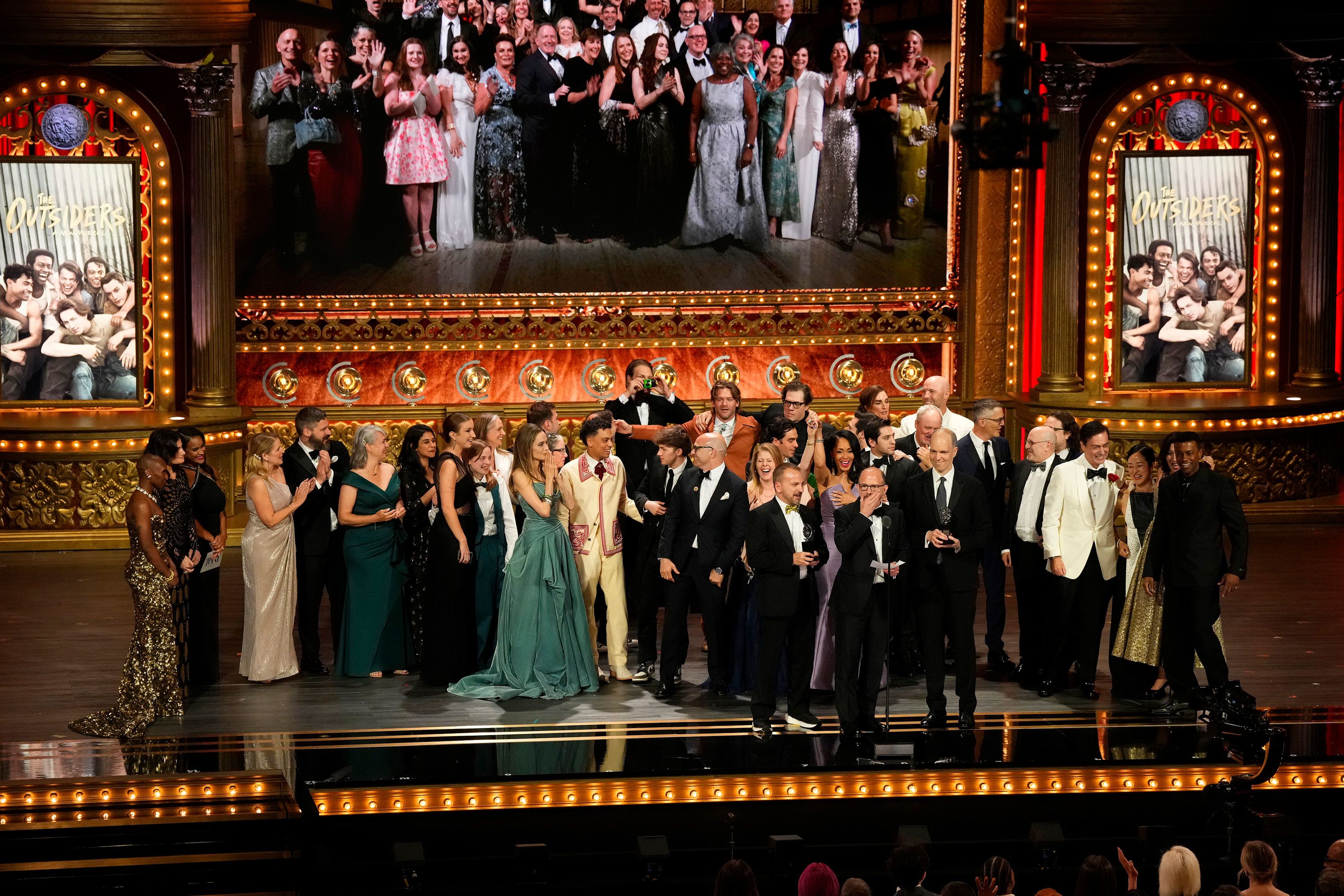 Cast and crew members from the musical "The Outsiders" accept the award for best musical.