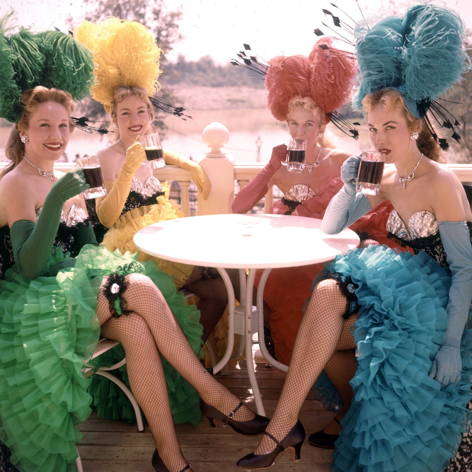 Showgirls sit at an outdoor table.
