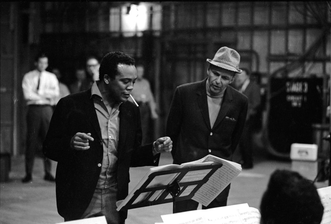 American jazz musician, arranger, and composer Quincy Jones (left) works with singer and actor Frank Sinatra on a soundstage, 1964.