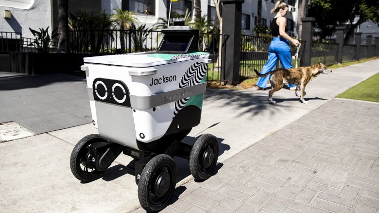 A delivery robot by the company Serve Robotics moves past a woman walking a dog, in Los Angeles, California, in September 2022.