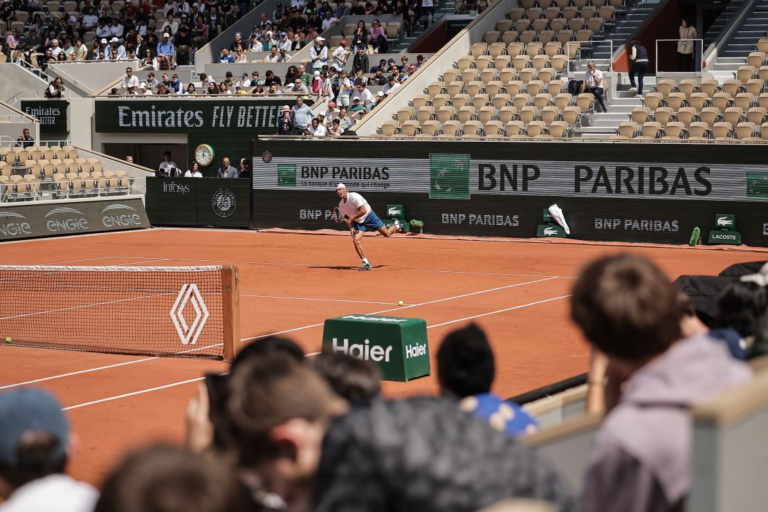 Rafael Nadal berlatih di Roland Garros di Paris dengan logo mengapit lapangan.