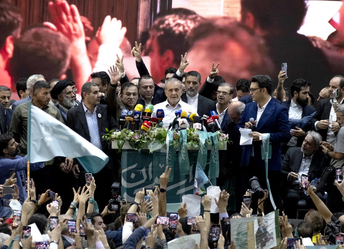 Reformist lawmaker and Iran's 2024 presidential candidate, Masoud Pezeshkian (C), speaks while his supporters flash victory signs during an electoral campaign rally at a sports complex in downtown Tehran, Iran, on June 23.