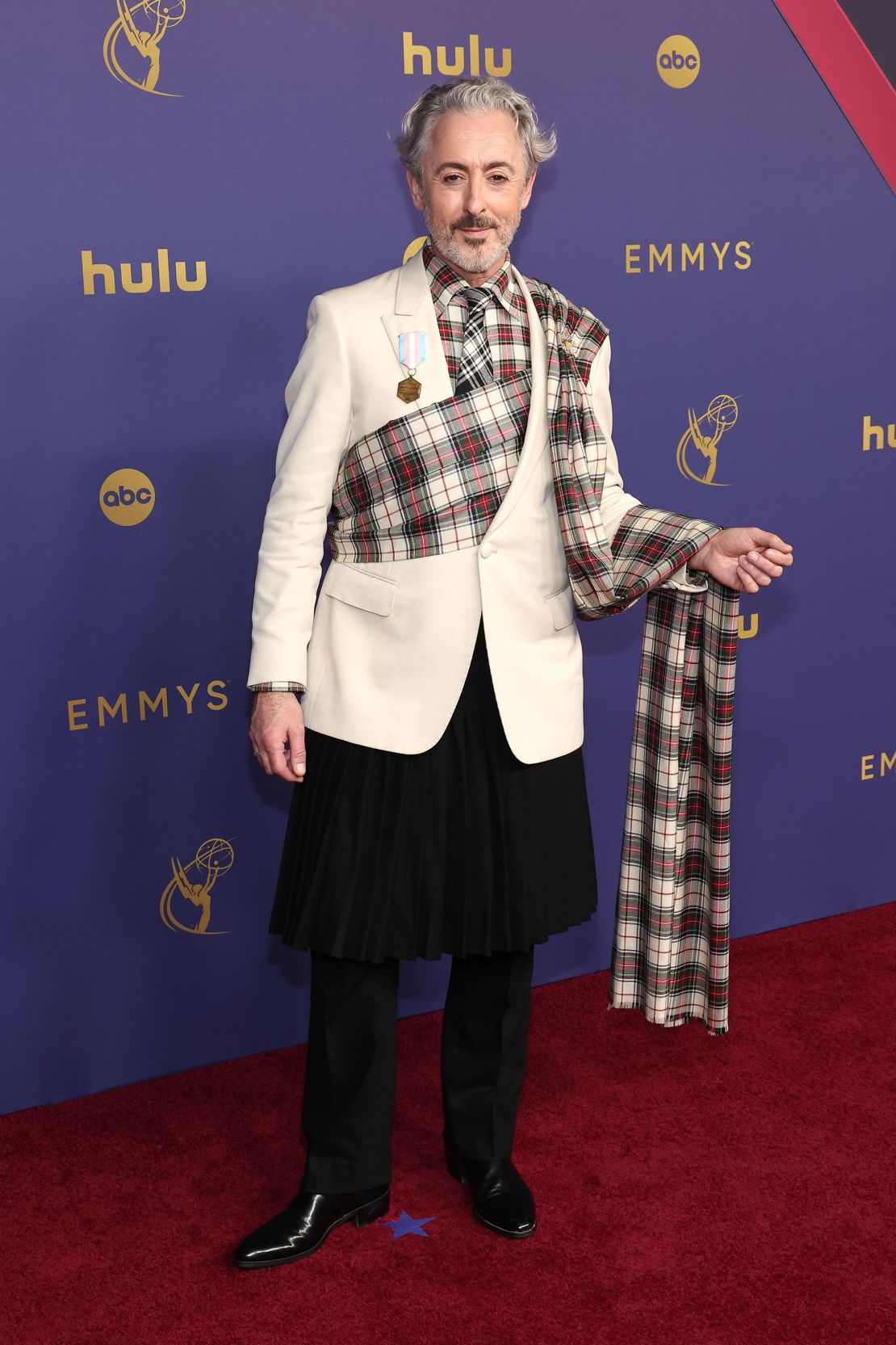 Alan Cumming in Teddy Van Ronson wore a black wool kilt with a pleated cummerbund train that doubled as a scarf from his cream jacket.