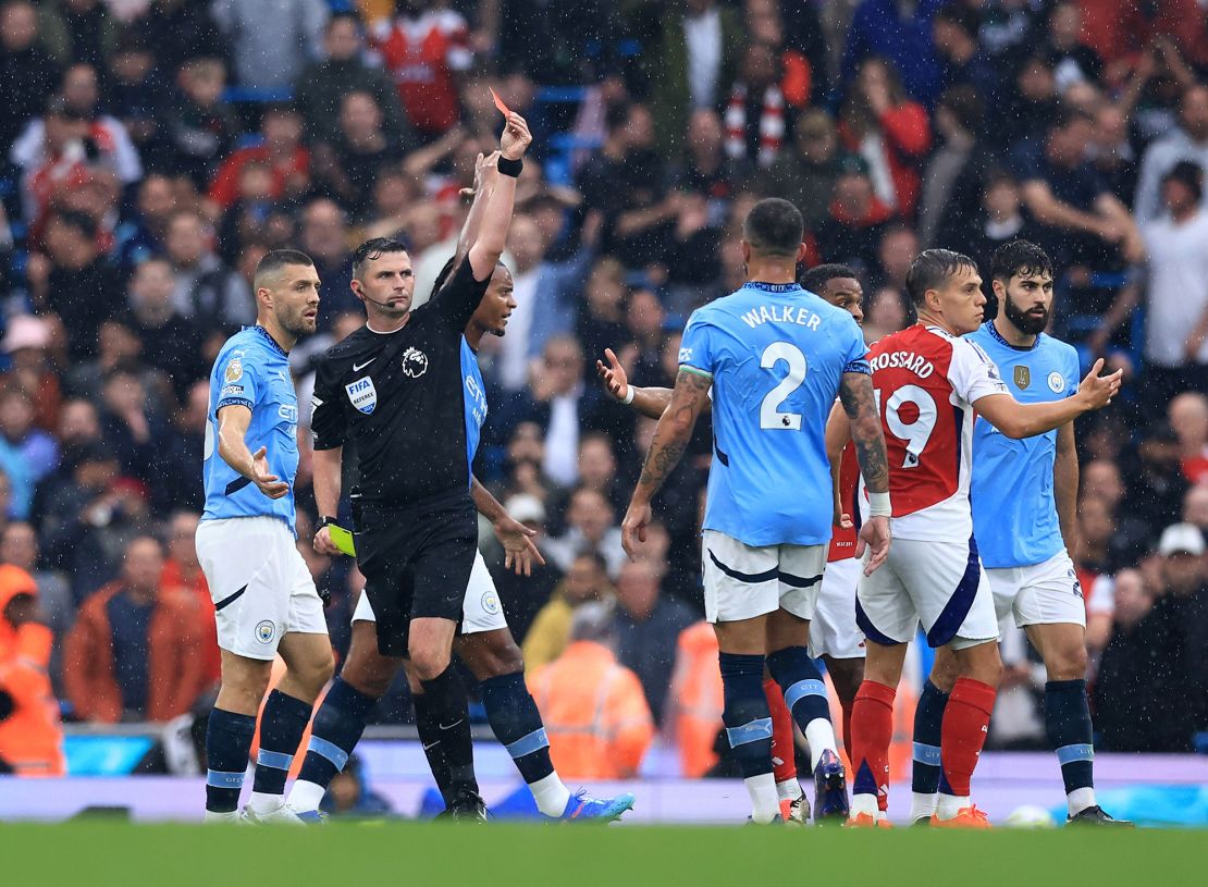 Trossard is dismissed by referee Michael Oliver.