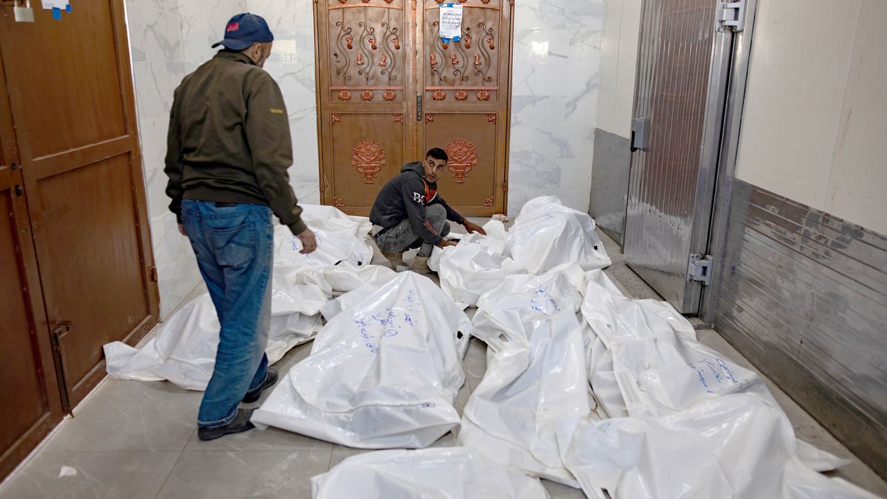 Two men stand next to the bodies of Palestinians killed following an Israeli airstrike, inside the European Hospital, Gaza, on October 25.