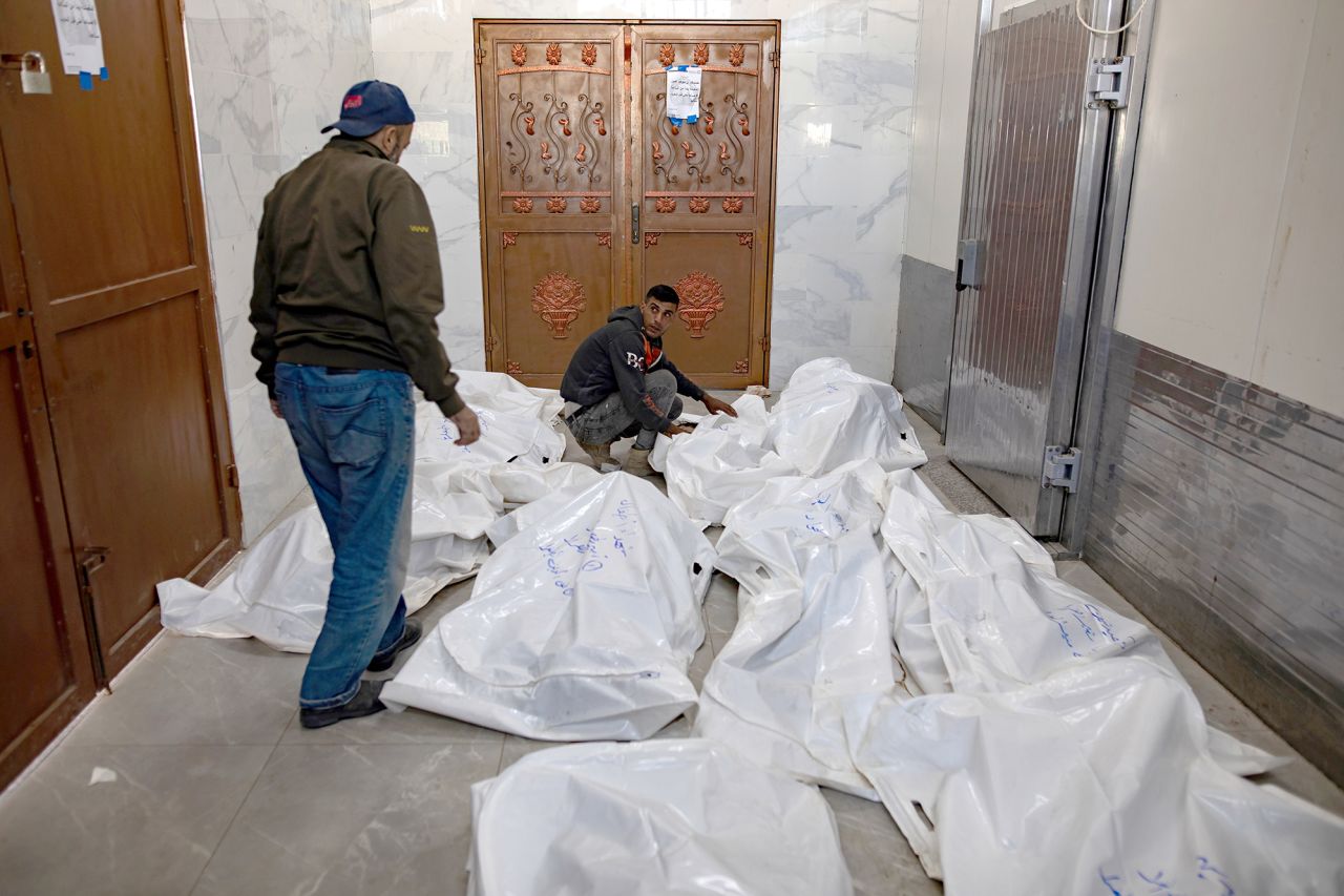 Two men stand next to the bodies of Palestinians killed following an Israeli airstrike, inside the European Hospital, Gaza, on October 25.