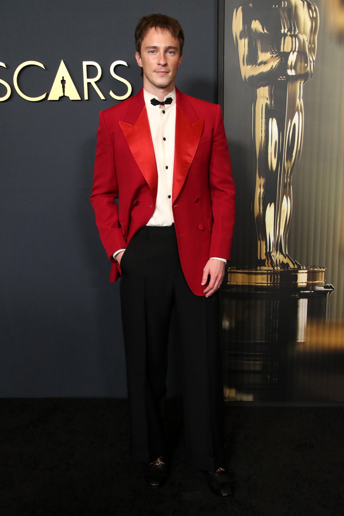 Drew Starkey paired his red suit with a stand collar and ornate black clasp.