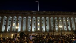 a crowd of people standing in front of a large building at night