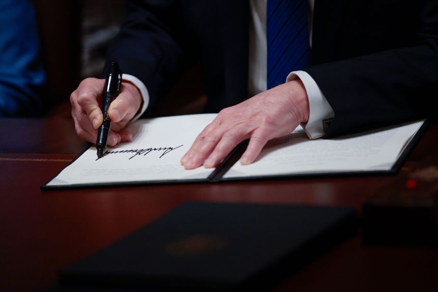 President Donald Trump signs executive orders prior to delivering remarks to the news media at the White House in Washington, DC, on March 25.