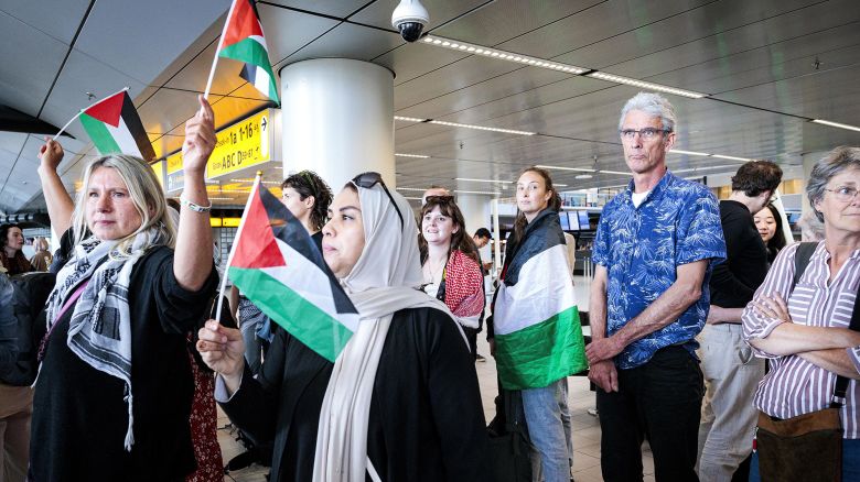 People wave Palestinian flags as participants in the 'Global March to Gaza' depart from Schiphol Airport for Egypt at Schiphol, The Netherlands on Wednesday.