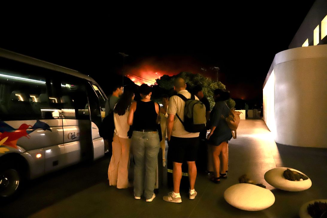 Tourists evacuate a hotel on Crete as wildfires burn.