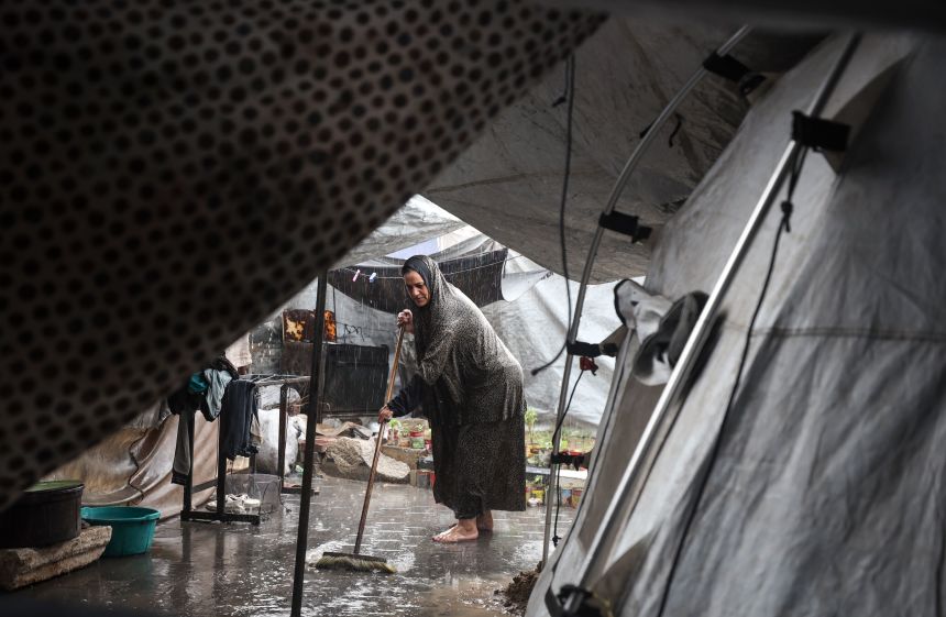 A displaced Palestinian woman forces water out of her tent after a rainstorm in Gaza, Palestine, dumped heavy rain at a makeshift camp inside the Gaza port on Friday.