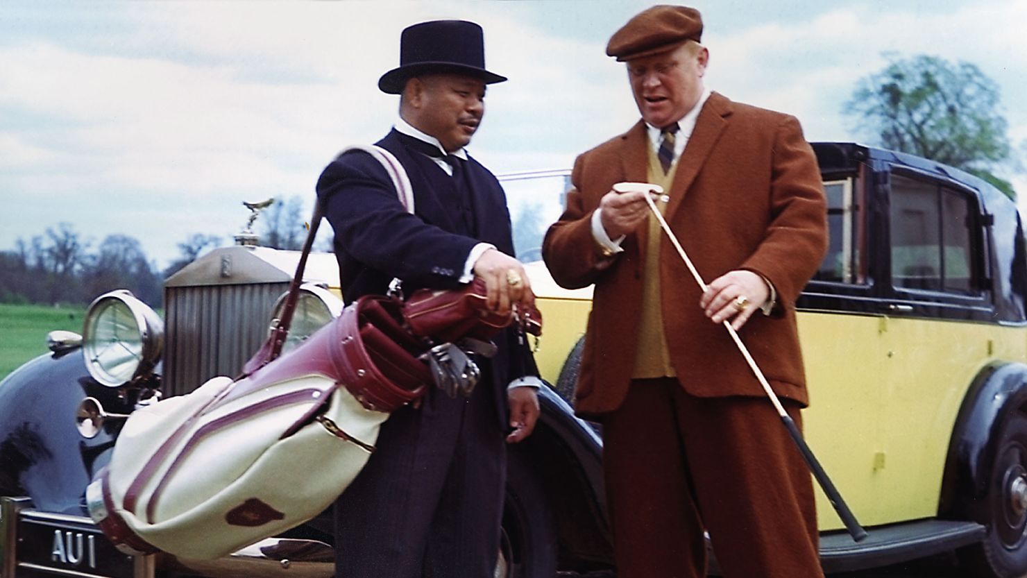 Harold Sakata and Gert Frobe in James Bond movie "Goldfinger" (1964) standing in front of a 1937 Rolls-Royce Phantom III Sedanca de Ville
