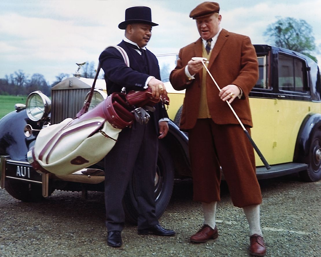 Harold Sakata and Gert Frobe in James Bond movie "Goldfinger" (1964) standing in front of a 1937 Rolls-Royce Phantom III Sedanca de Ville.