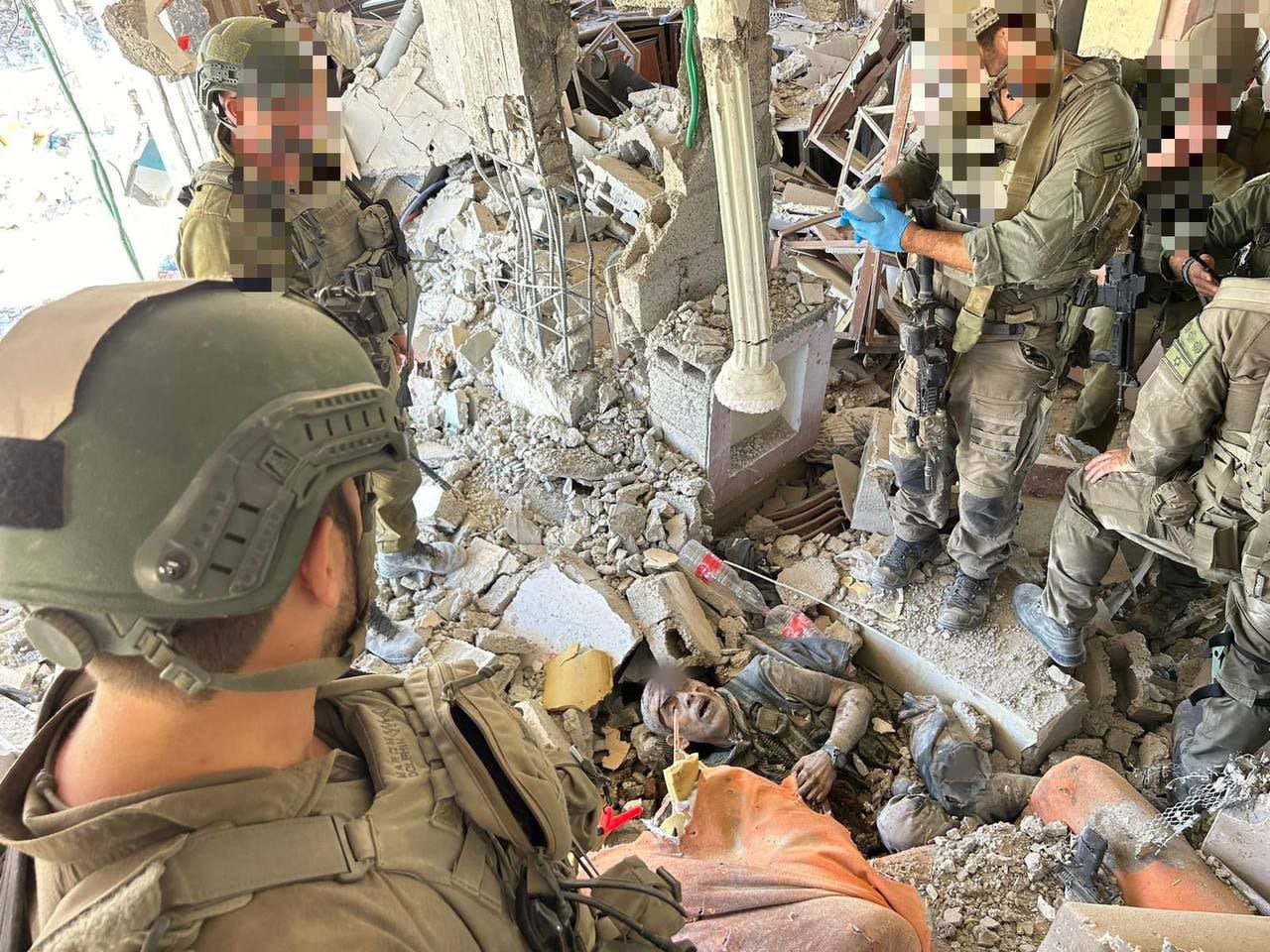 This image appears to show the body of Hamas leader Yahya Sinwar lying in the rubble of a destroyed building, with Israeli soldiers standing around the body.