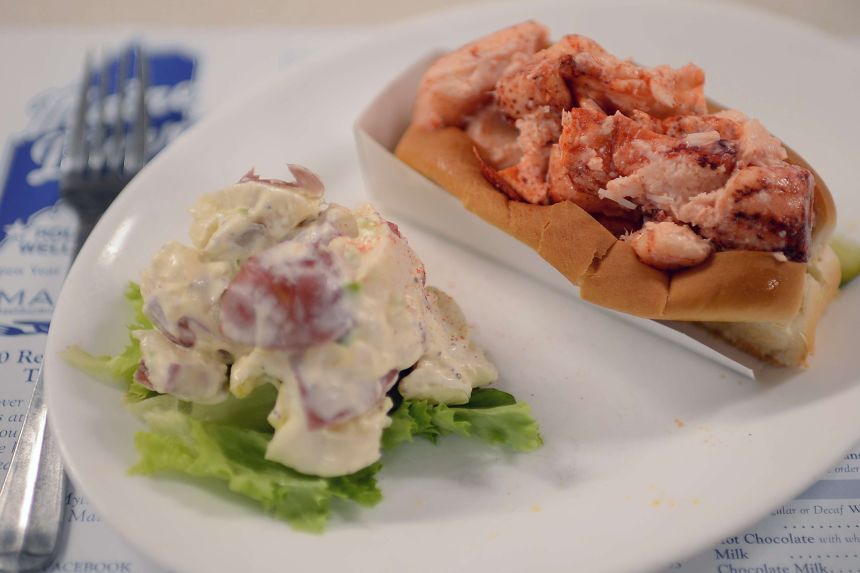 A lobster roll with a side of potato salad is served at Maine Diner in Wells, Maine.