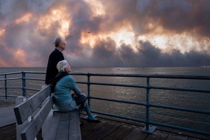 People watch from the Santa Monica Pier as smoke grows from the Palisades Fire.