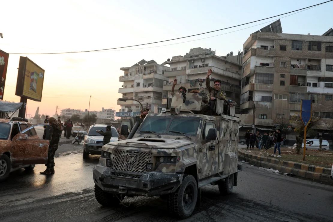 Los combatientes sirios antigubernamentales vitorean mientras viajan en un vehículo militar por las calles de Hama el 5 de diciembre de 2024.