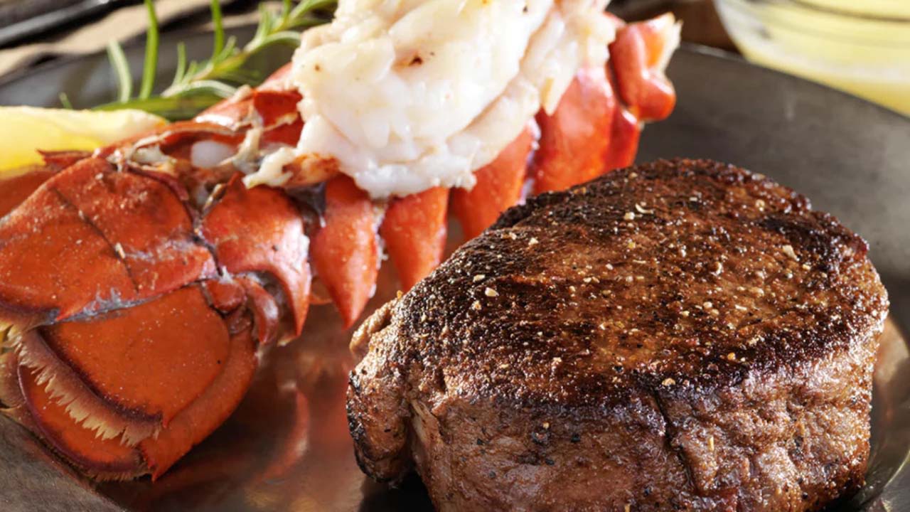 Lobster and steak with garnish on a plate.