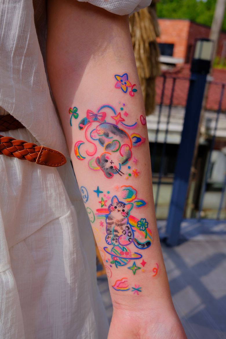 Sisi's tattoos feature bright colors, cartoonish illustrations and a playful style.