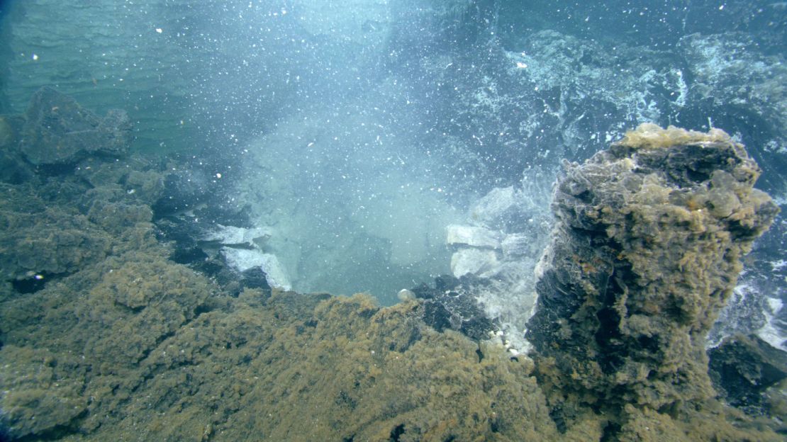 White clouds of microbial waste billow from the seafloor.