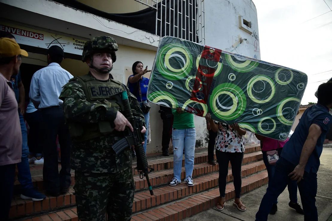 Un soldado hace guardia mientras la gente descarga ayuda humanitaria para las personas desplazadas por los recientes enfrentamientos entre grupos armados en Tibú, departamento de Norte de Santander, Colombia, el domingo