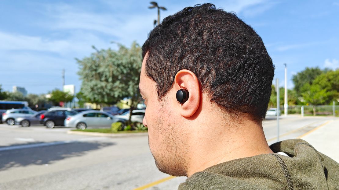 A side view of a man wearing a black wireless earbuds.