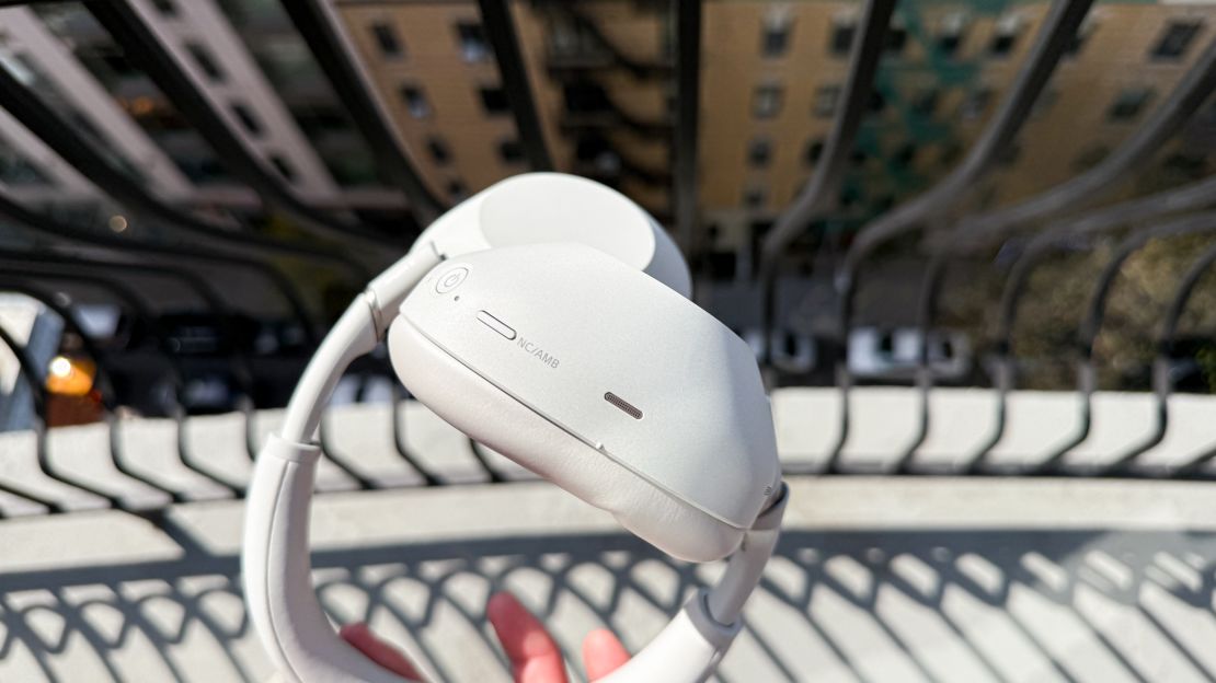 A closeup of the NC/AMB button on the white Sony XM6.