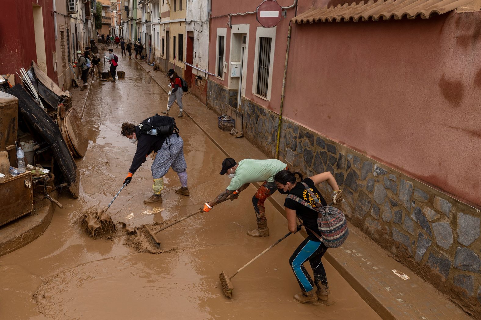 People clear mud from a street in Valencia on Monday.