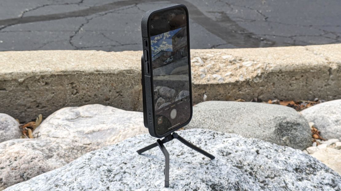 The Spigen MagFit+ Tripod Phone Stand holds an iPhone atop a rock