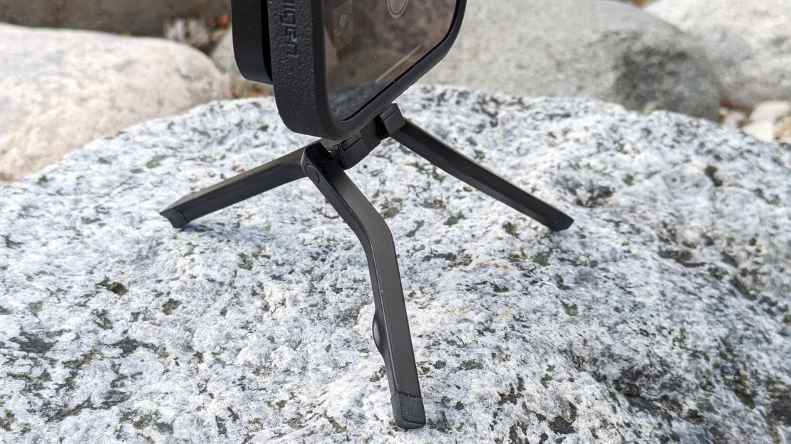 A close-up of the three legs of the Spigen MagFit+ Tripod Stand, which is on a rock, as a phone is mounted.