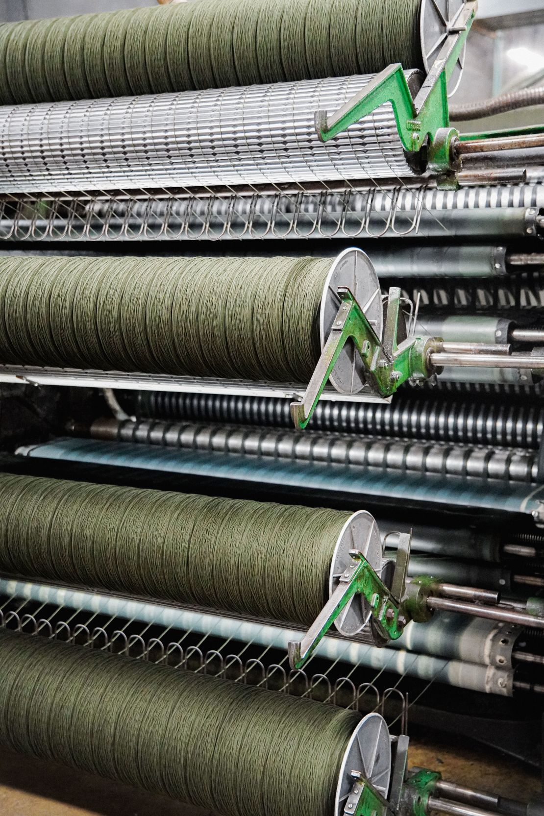 Following carding, where wool fibers are disentangled and aligned, the brushed wool is condensed and rolled again into strips that are then spun onto large spools during the roving process. From there, those spools go onto the spinning machines where they get spun into spools of yarn.